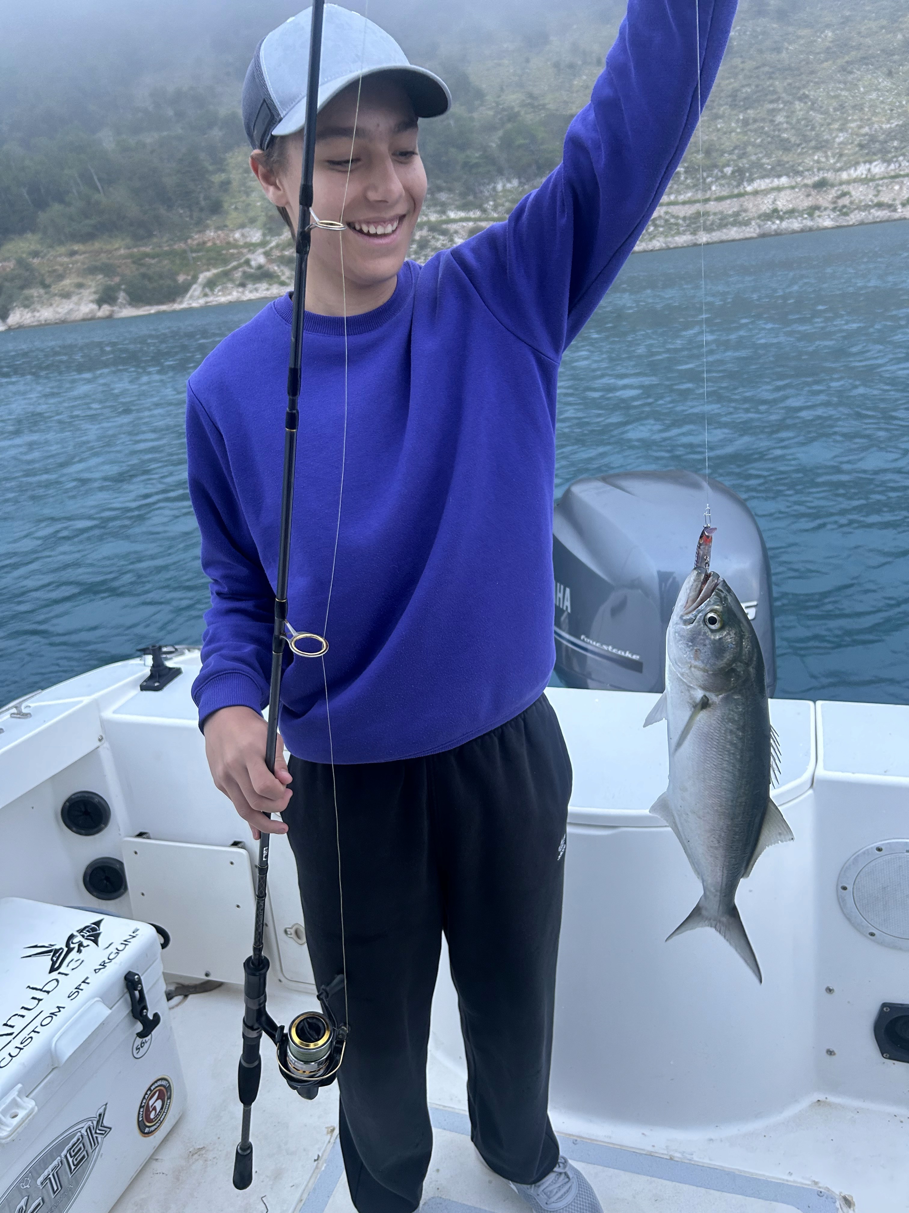 Child having fun catching fish during a family fishing trip on the Adriatic Sea.