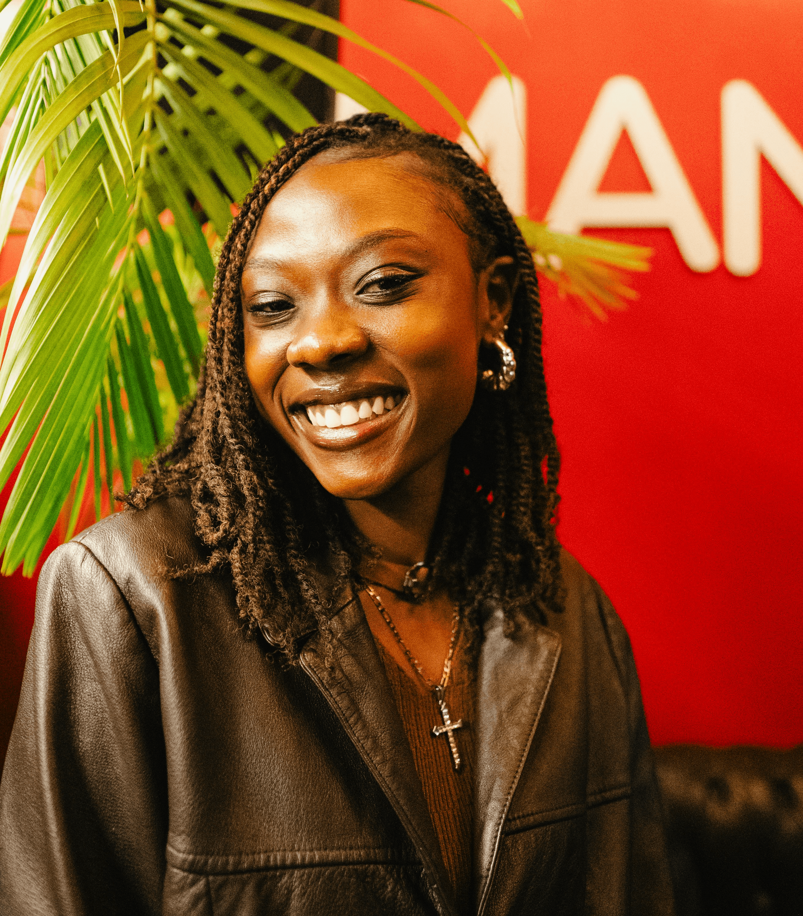A smiling woman with braided hair and a leather jacket.