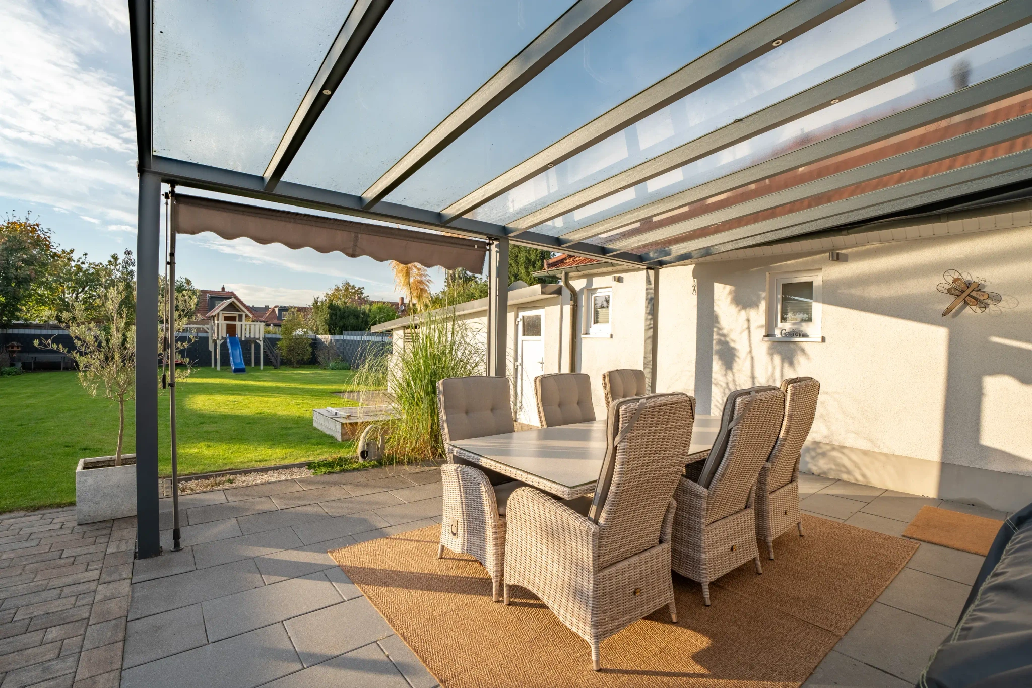 Überdachte Terrasse mit Esstisch und Blick in den gepflegten Garten eines Einfamilienhauses in Gronau – Westfalen Wohnen.