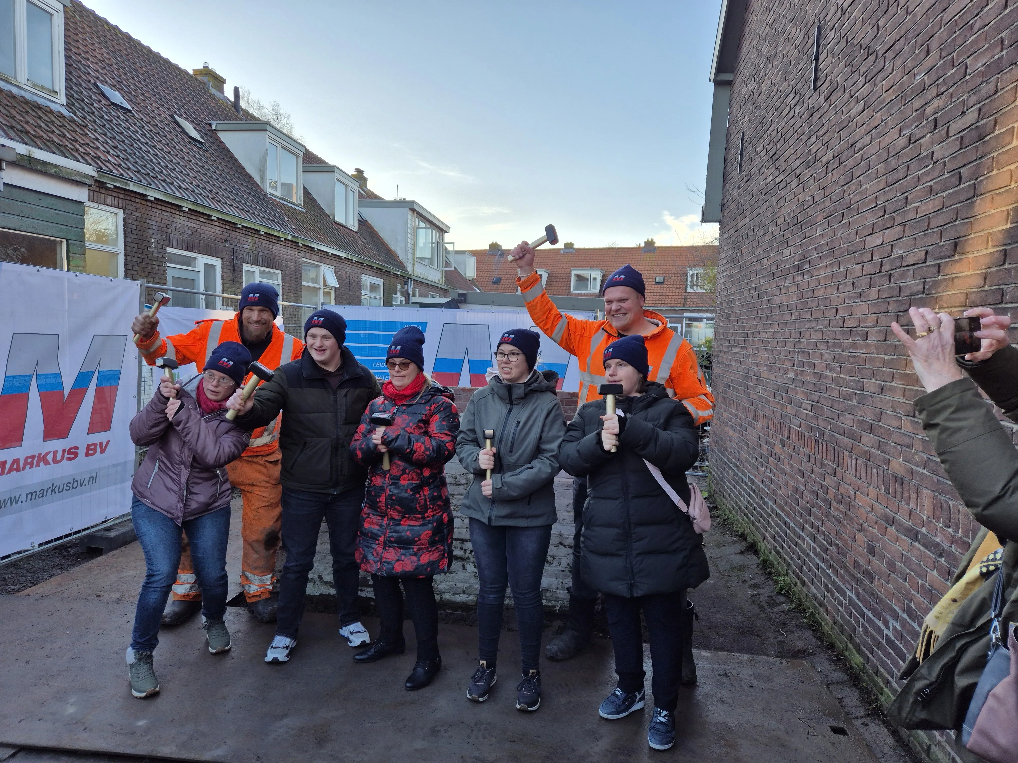 De bewoners bij de sloop van de eerste muur van het oude pand van hun nieuwe woningen