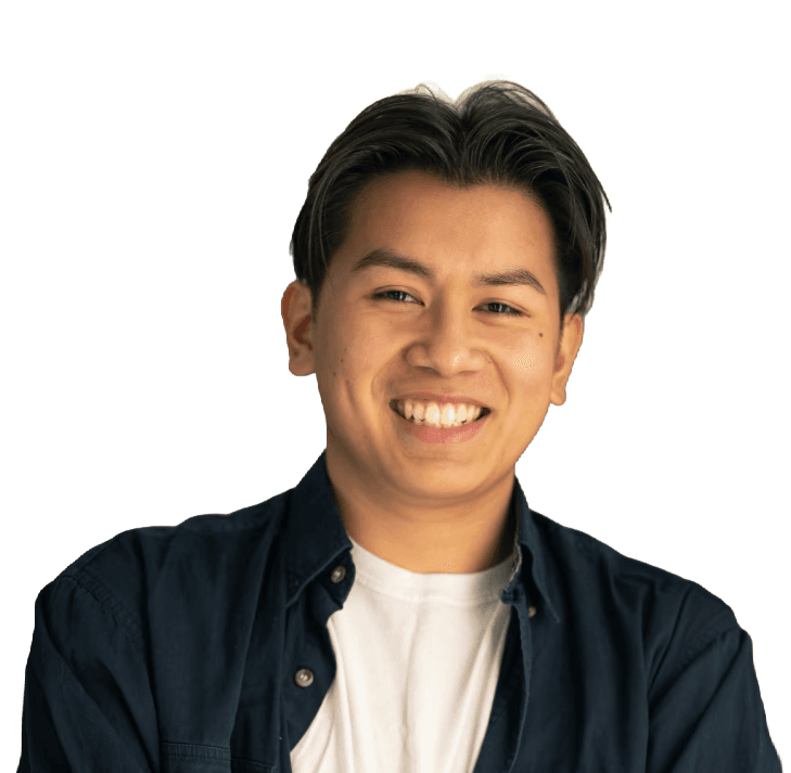 Young man in a blue shirt smiles with arms crossed. (Background Removed)