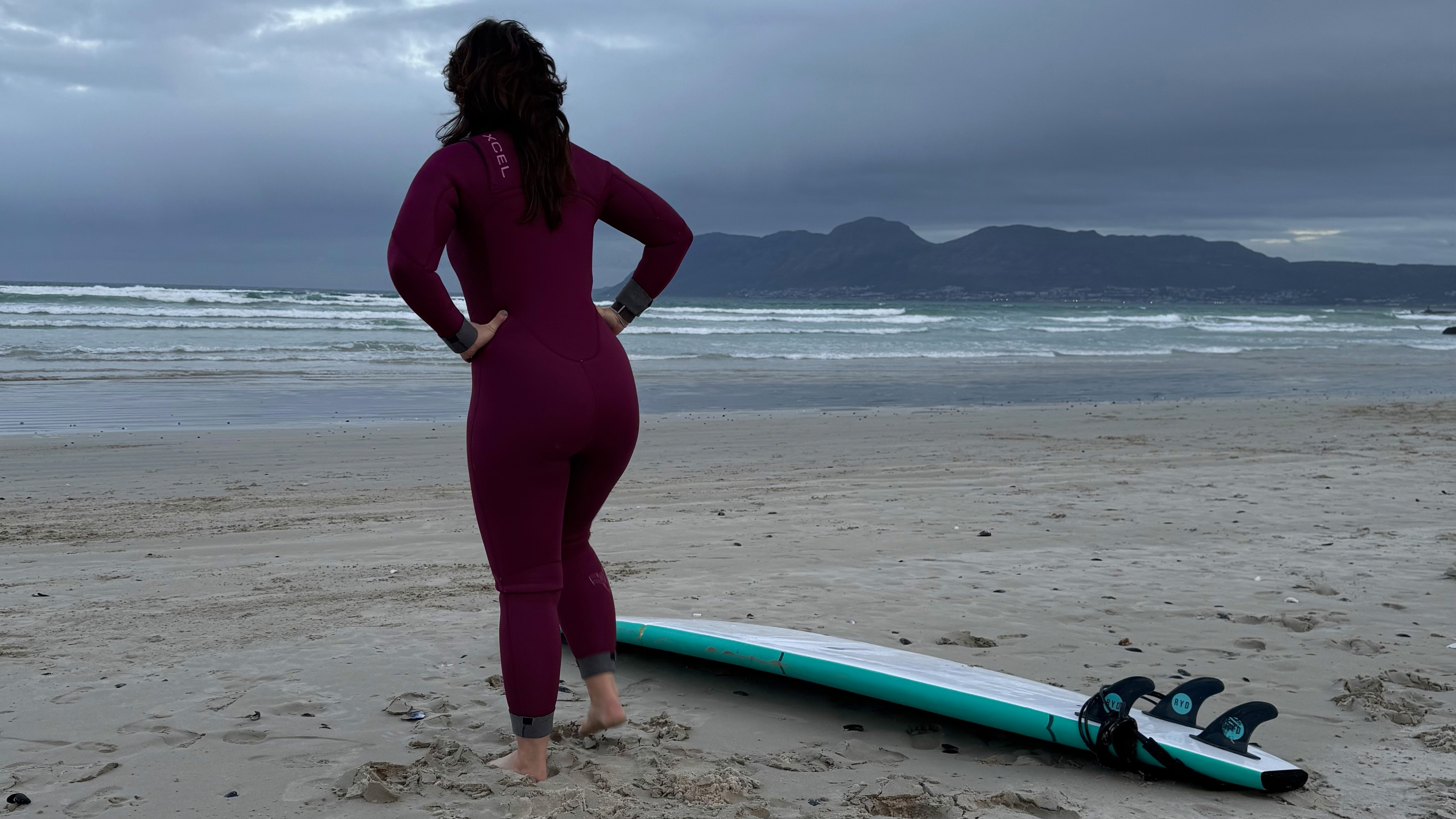 Femaler surfer at Muizenberg Beach in Cape Town, warming up before her surf lesson