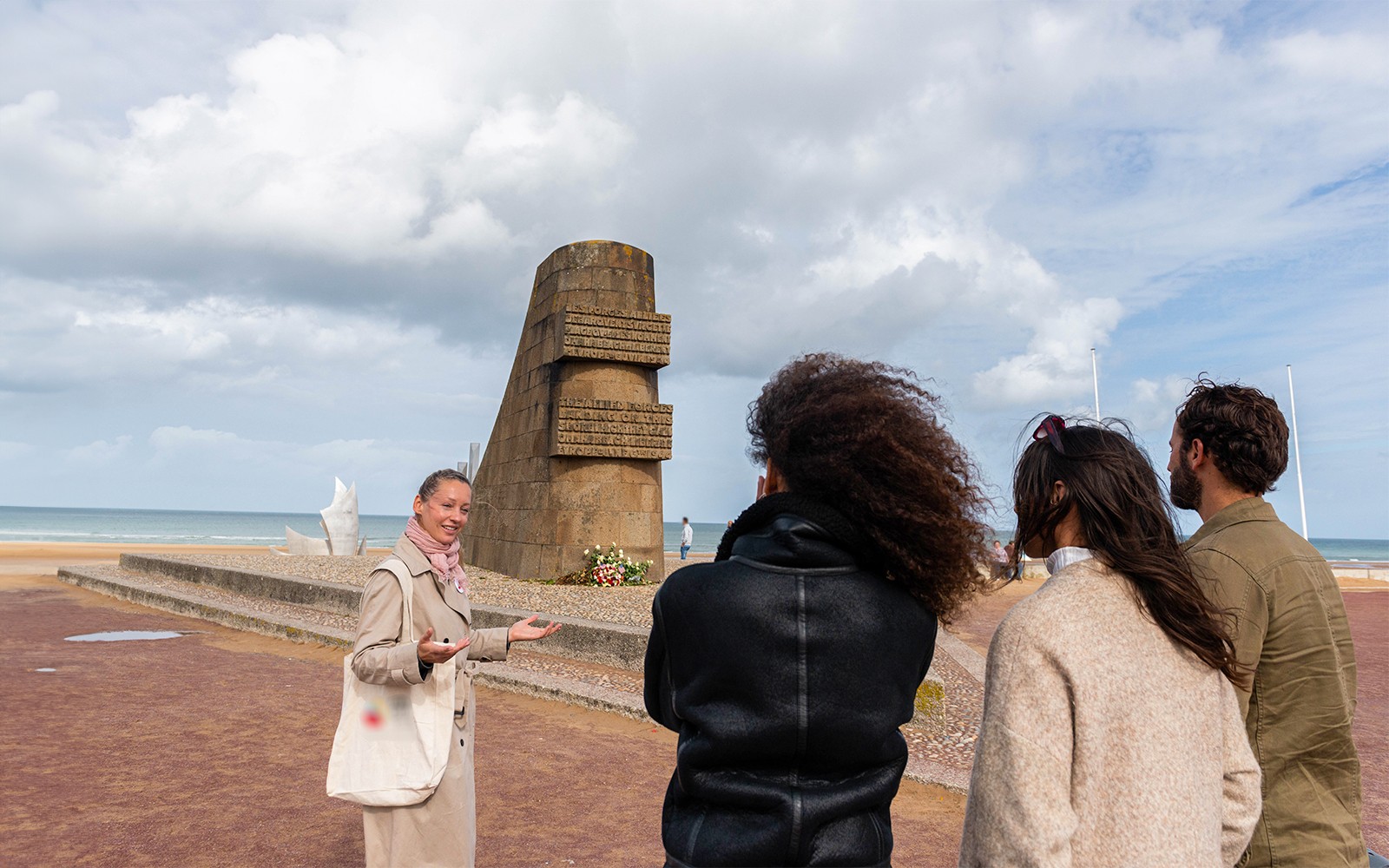 Guide explaining Omaha Beach Memorial to visitors in Normandy.