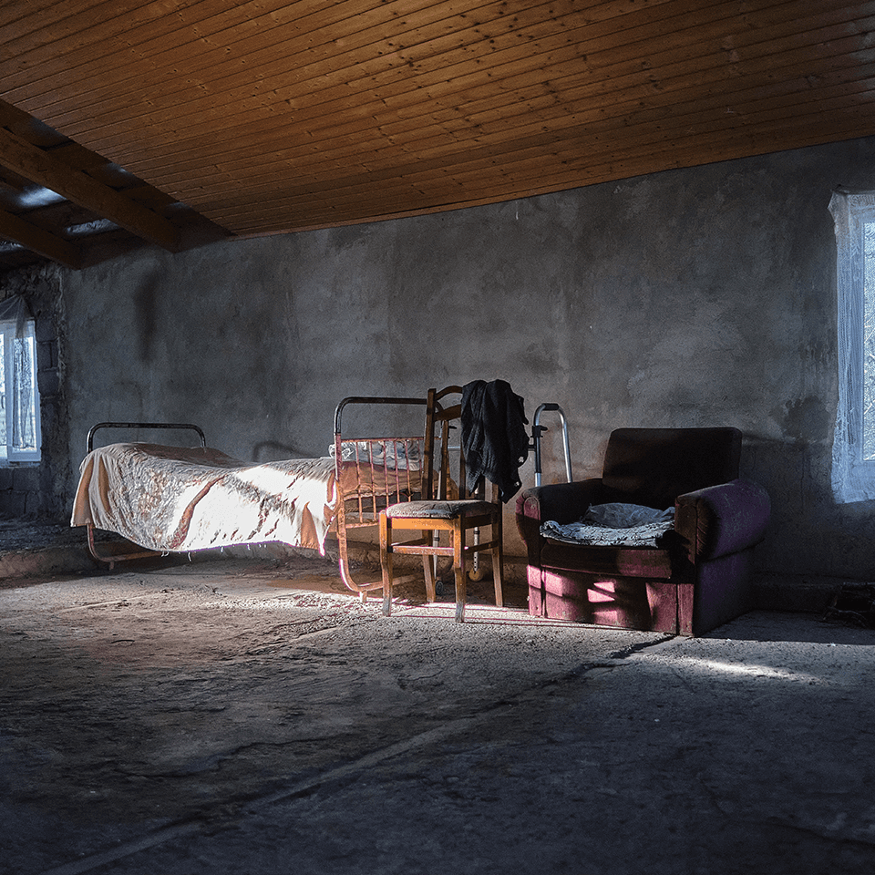 A bare, dilapidated room with a single bed
