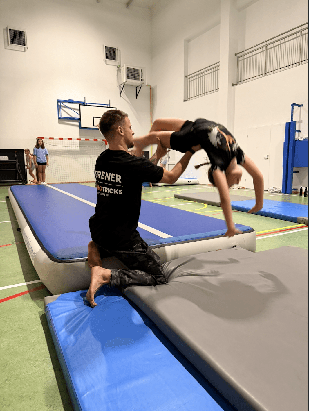 Trener mikołaj asekuruje uczennicę do fiflaka