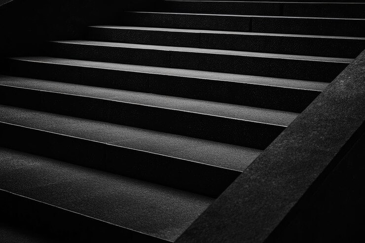 grayscale photo of man standing in front of stairs