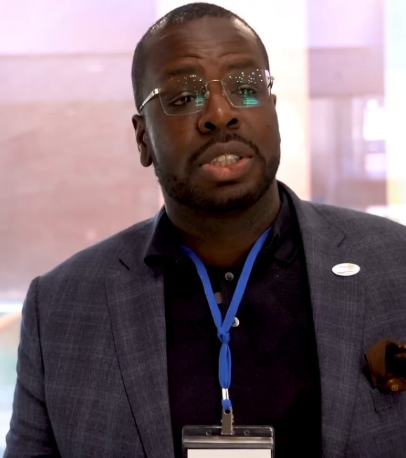 Profile portrait of a man in a white shirt against a light background