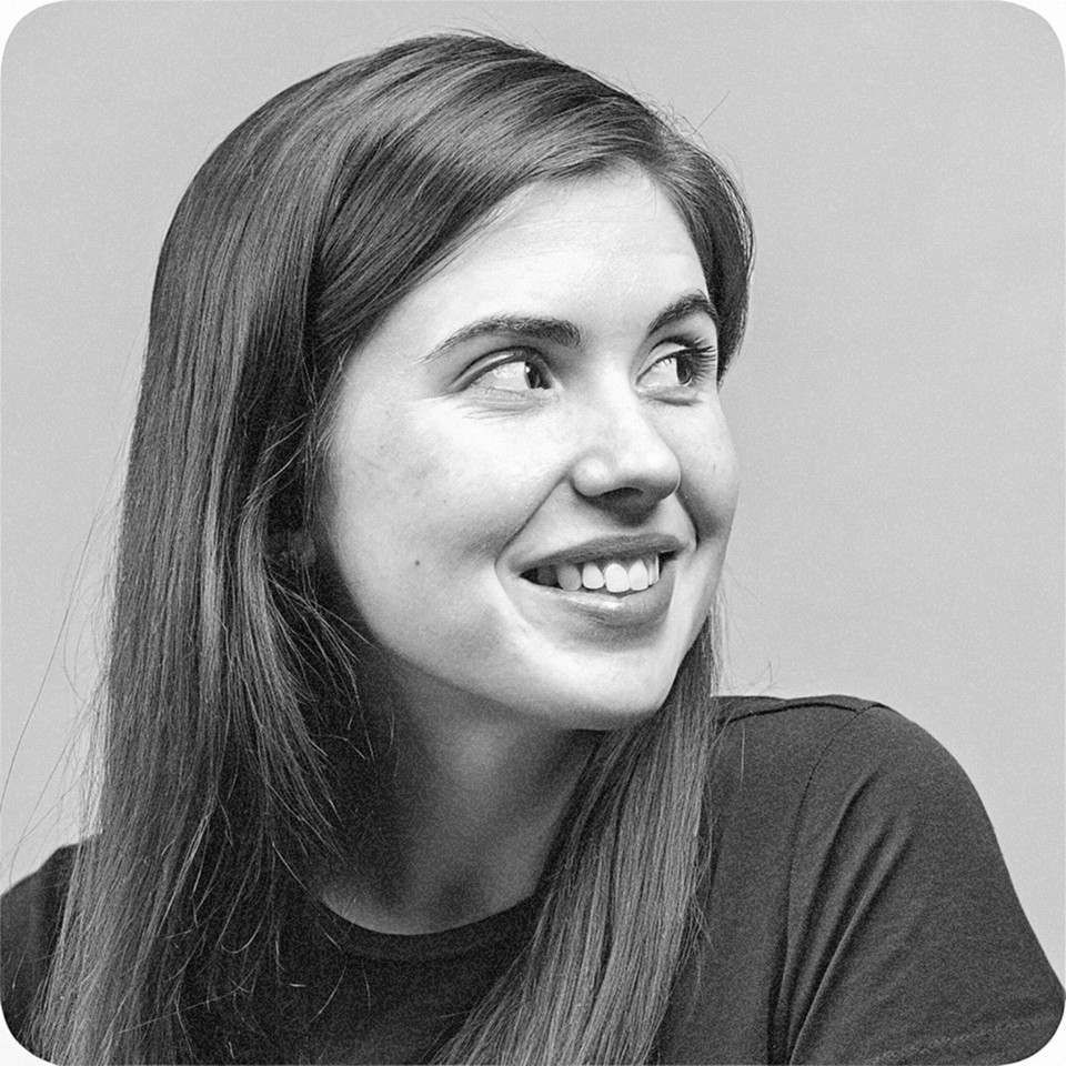 Portrait of a woman with straight long hair, in a dark t-shirt, set against a neutral backdrop.