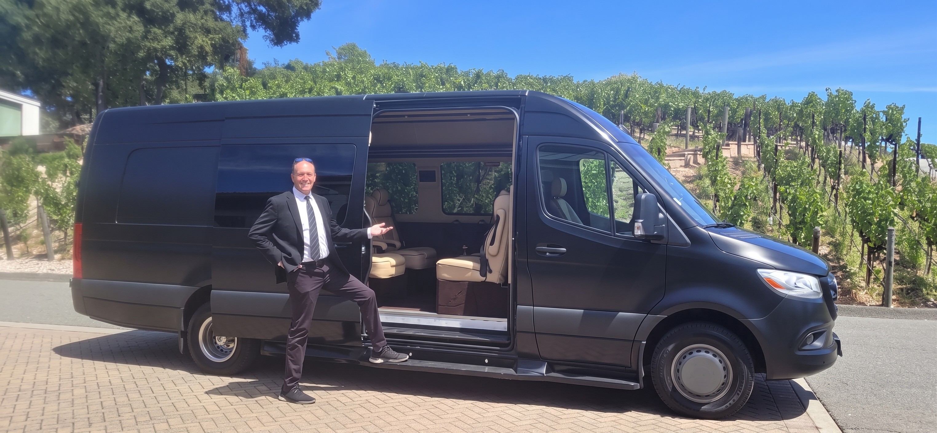 Charlie Portello, founder of The Vine Key, beside a black Mercedes Sprinter in wine country