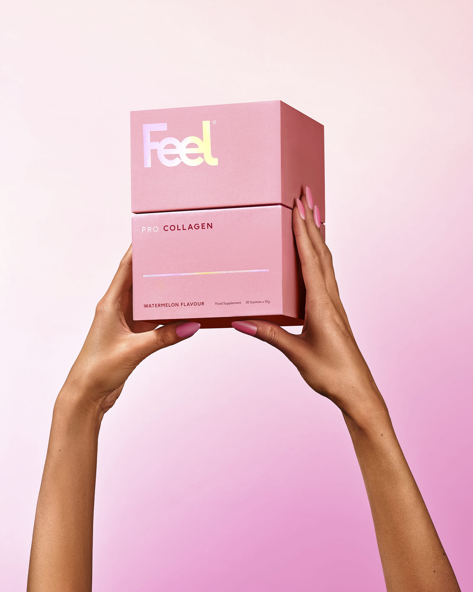 A pair of hands holds a pink box against a soft pink background, showcasing the product inside.