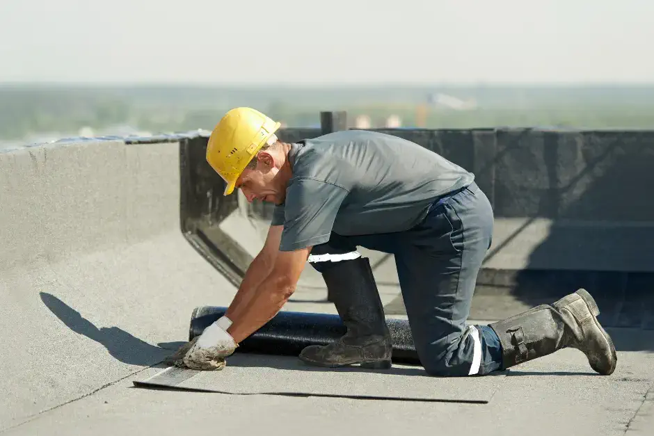 man installing flat TPO roof on commercial building