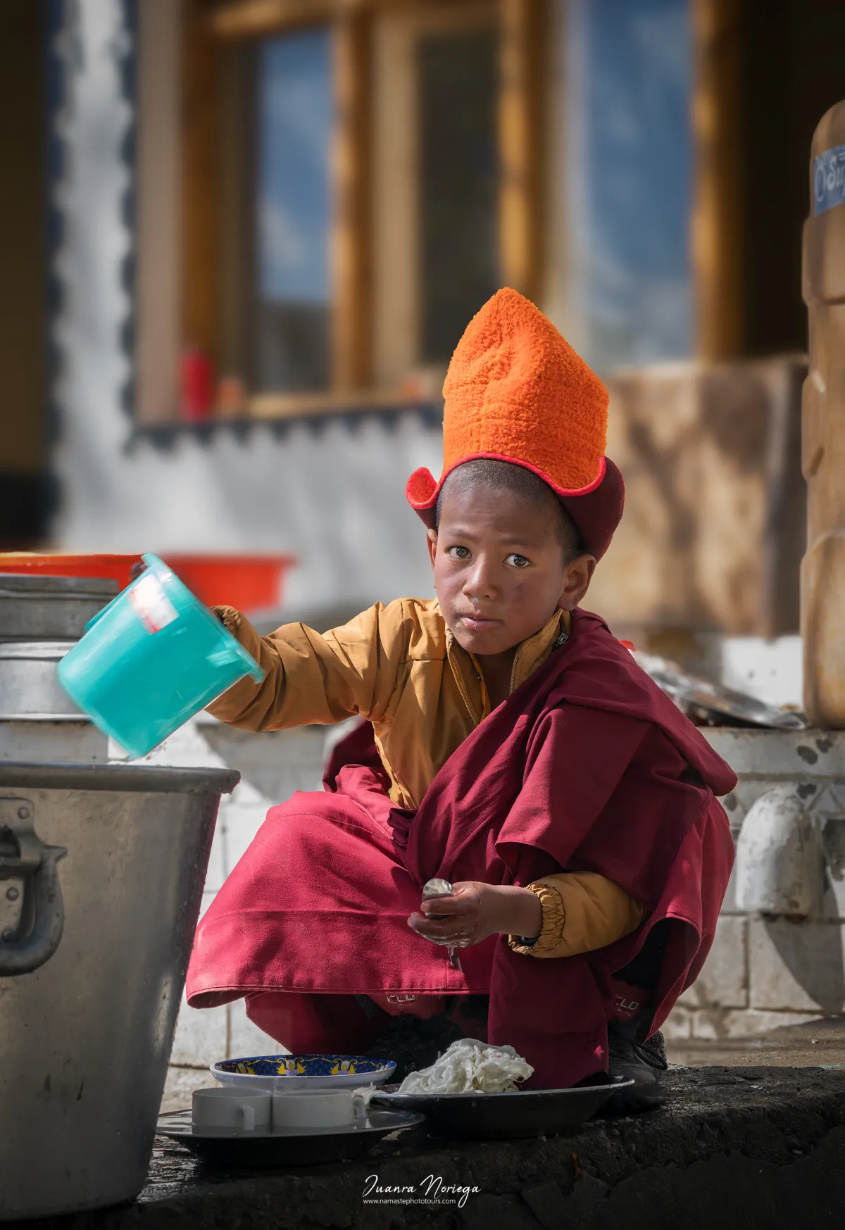 Niño novicio vertiendo agua en la cocina de un monasterio de Ladakh