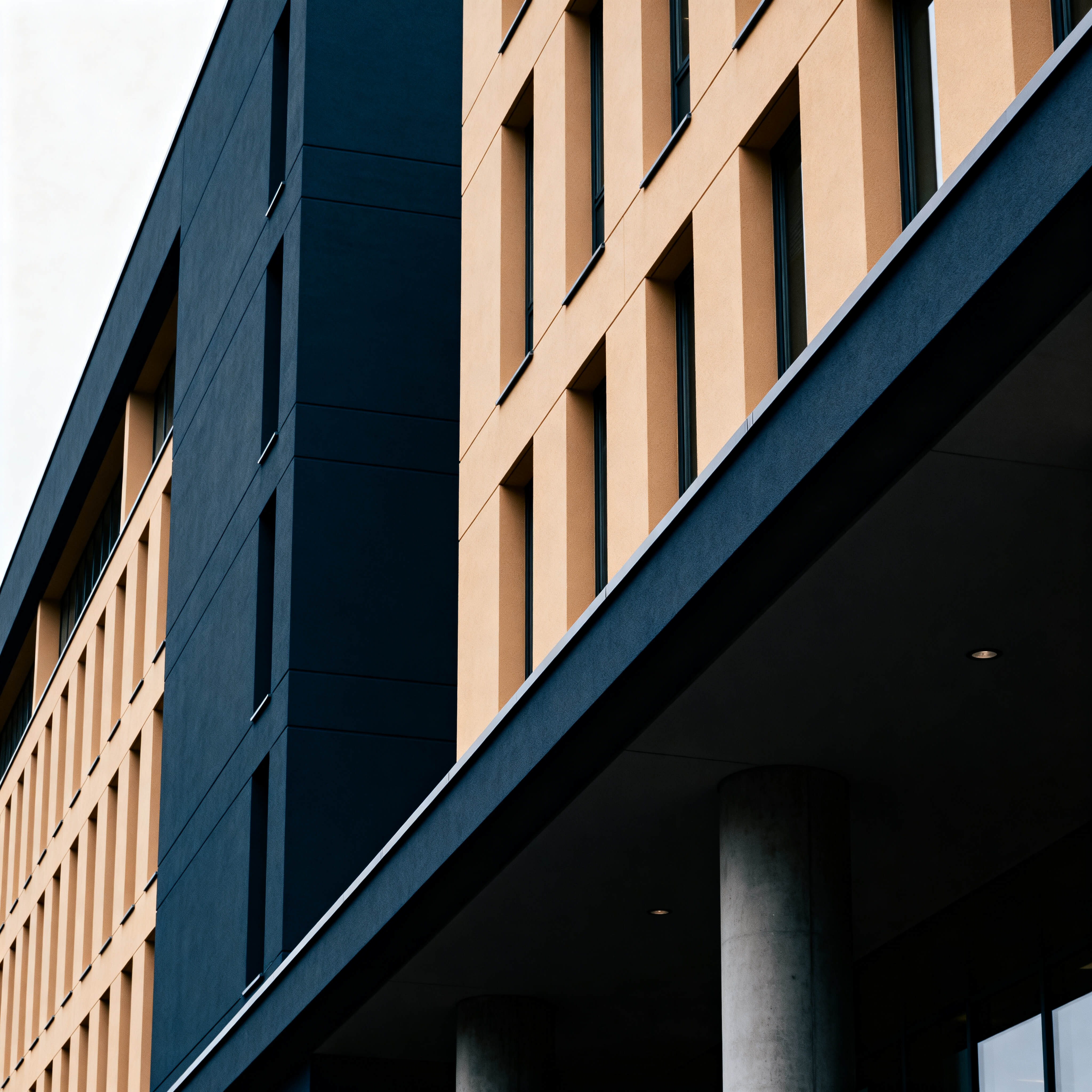 Fachada de prédio institucional moderno fotografada de baixo para cima com linhas arquitetônicas limpas e luz natural, representando o ambiente dos governos e organizações atendidos nas consultorias estratégicas.