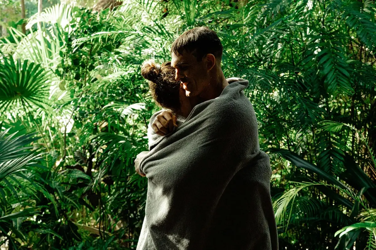 Couple embracing and drying off with a towel after swimming, surrounded by small trees in the jungle at Nômade Tulum, Mexico.