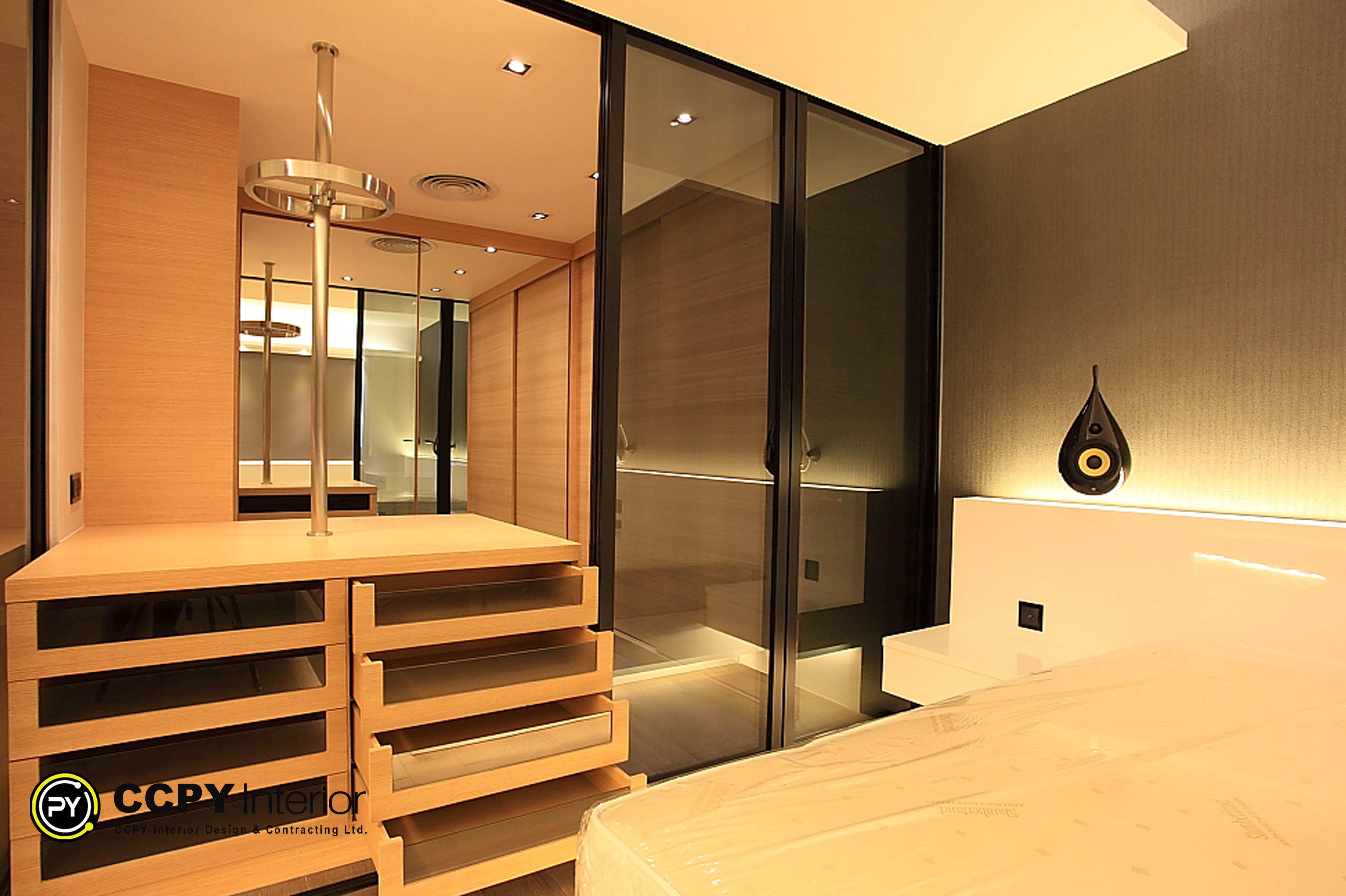 Luxury walk-in closet in Standalone House, Perkins Road with glass partitions, wooden storage modules, and a unique chrome rotating garment rack for boutique-style organization.