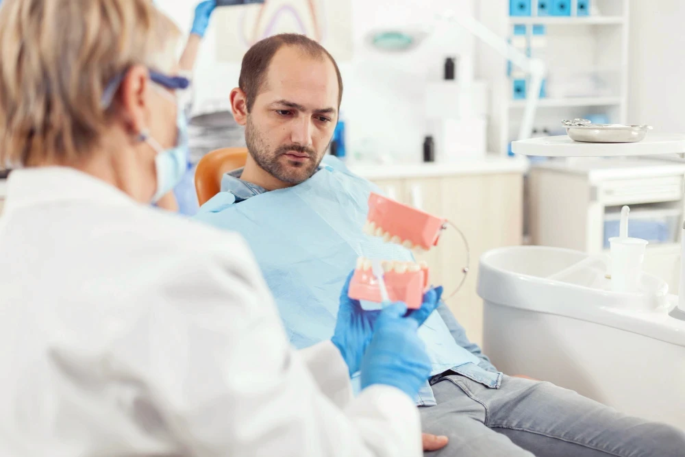 Dentist consulting with patient that is sitting in the exam chair.