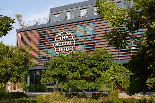 Exterior view of The Social Hub, a modern building with a wood-like facade and rooftop terrace.