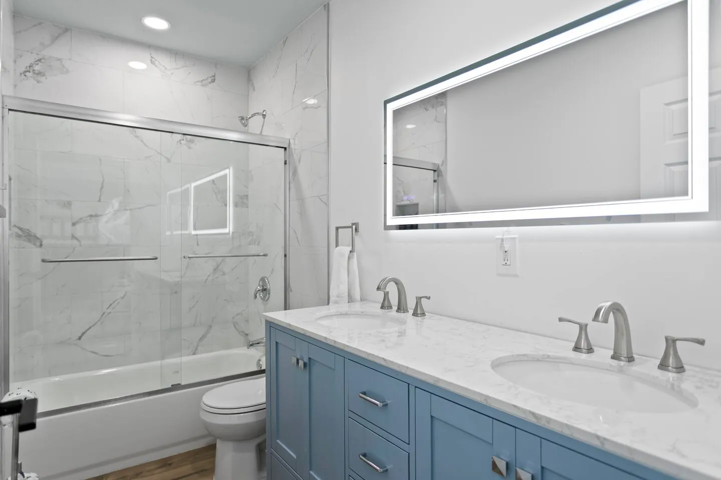 Bath with double vanity, lit mirror and blue cabinet at Salty House, Bradenton, Florida