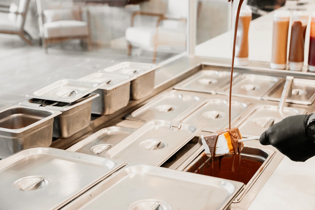 Behind-the-scenes photo of chocolate dipping station at Drizzle Cheesecakes.