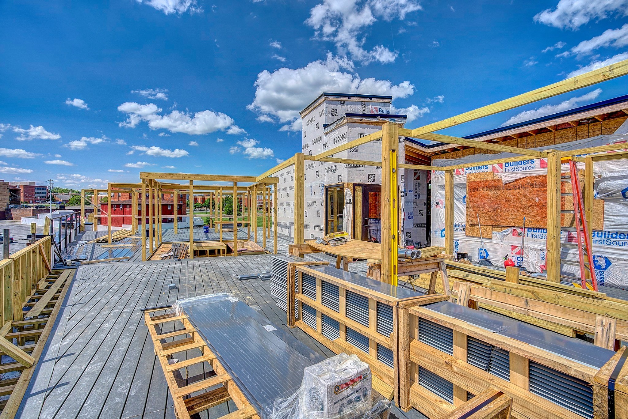 A modern building exterior with large windows, blue sky, and clouds in the background, showcasing contemporary architecture.