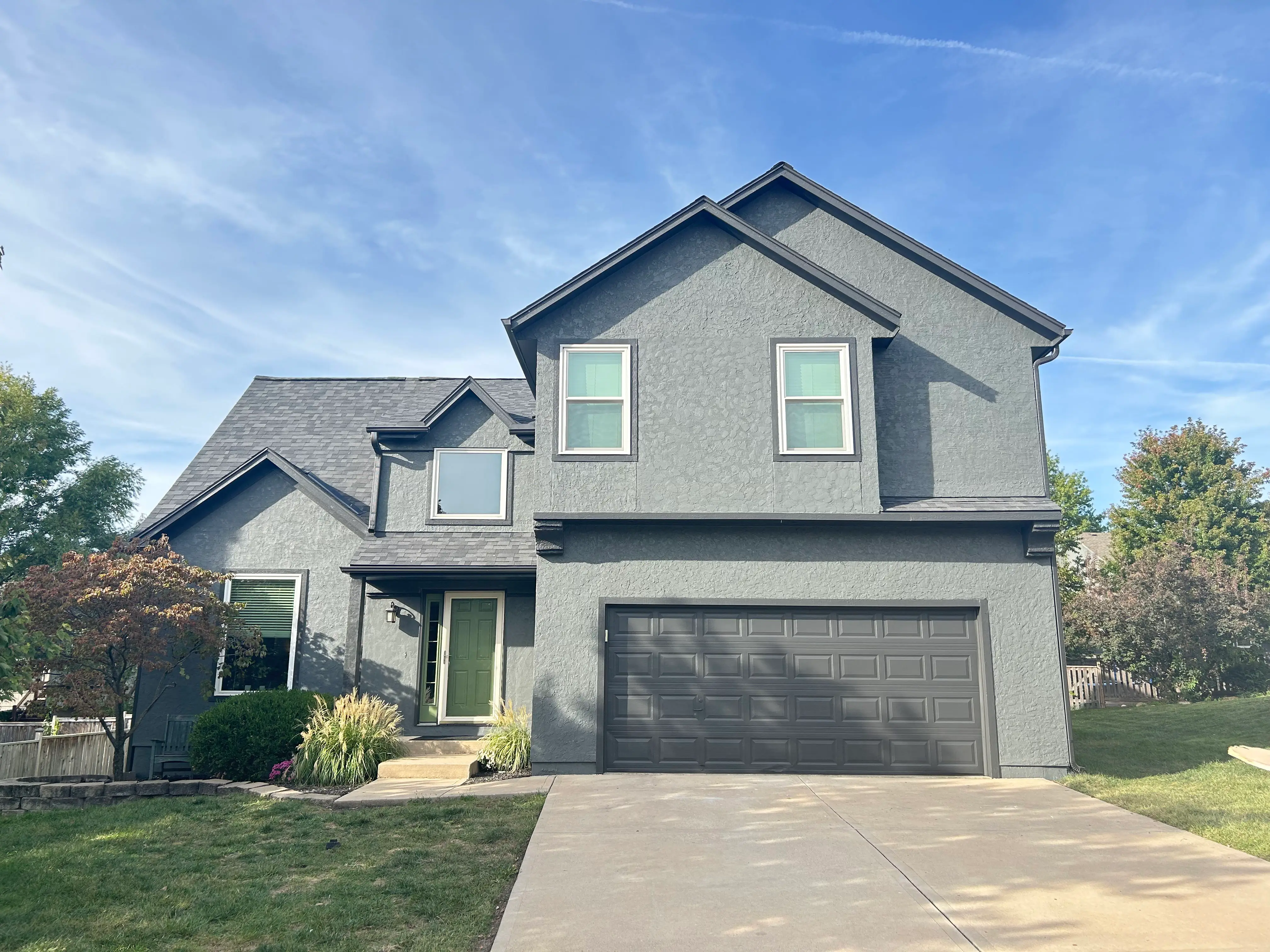 An image of a grey house with dark grey trim and a green door.