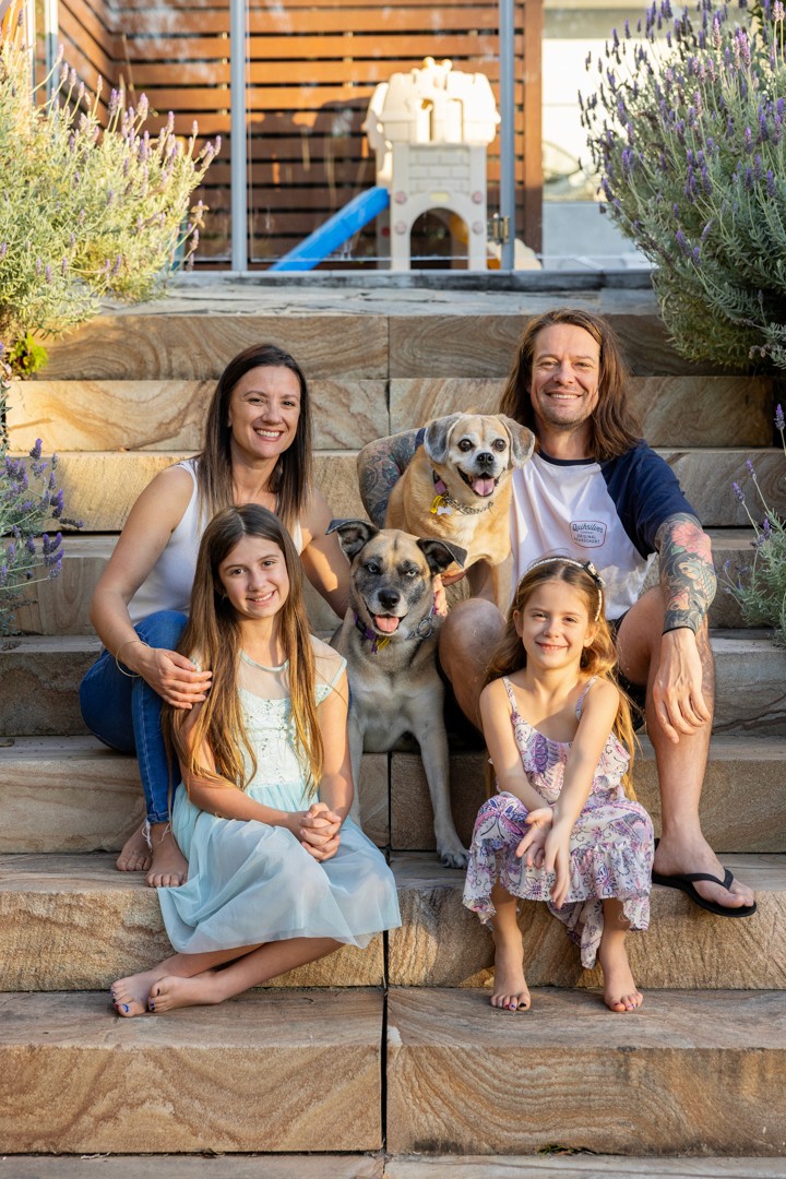 Young family sitting with dogs on sandstone stairs
