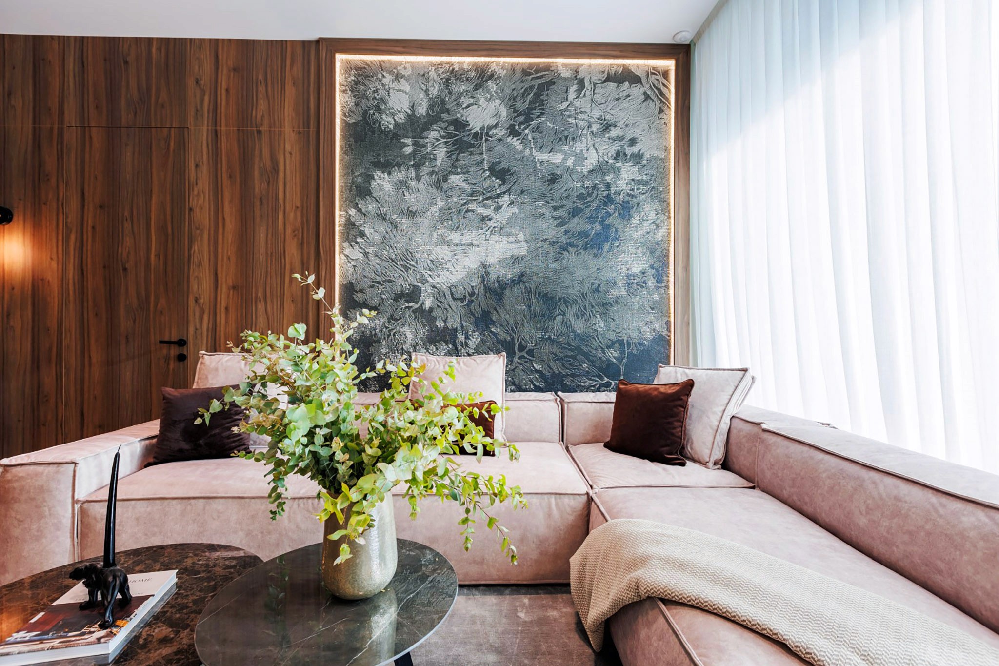 Villa Trio lounge with curved sectional sofa, statement artwork, and warm wood wall panels