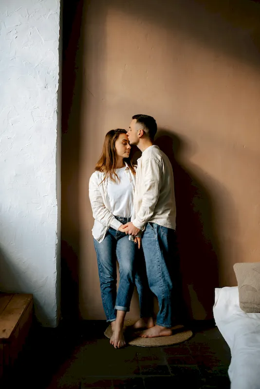 A couple leaning into each other in an aesthetic room with heavy shadows