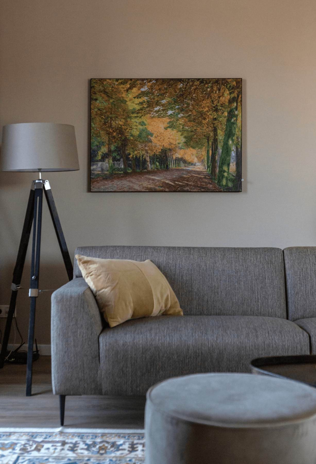 zithoek met taupe bank en schilderij van herfstbos
