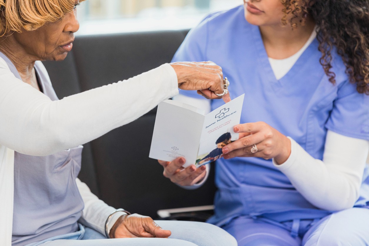 Senior and nurse discussing care options in brochure