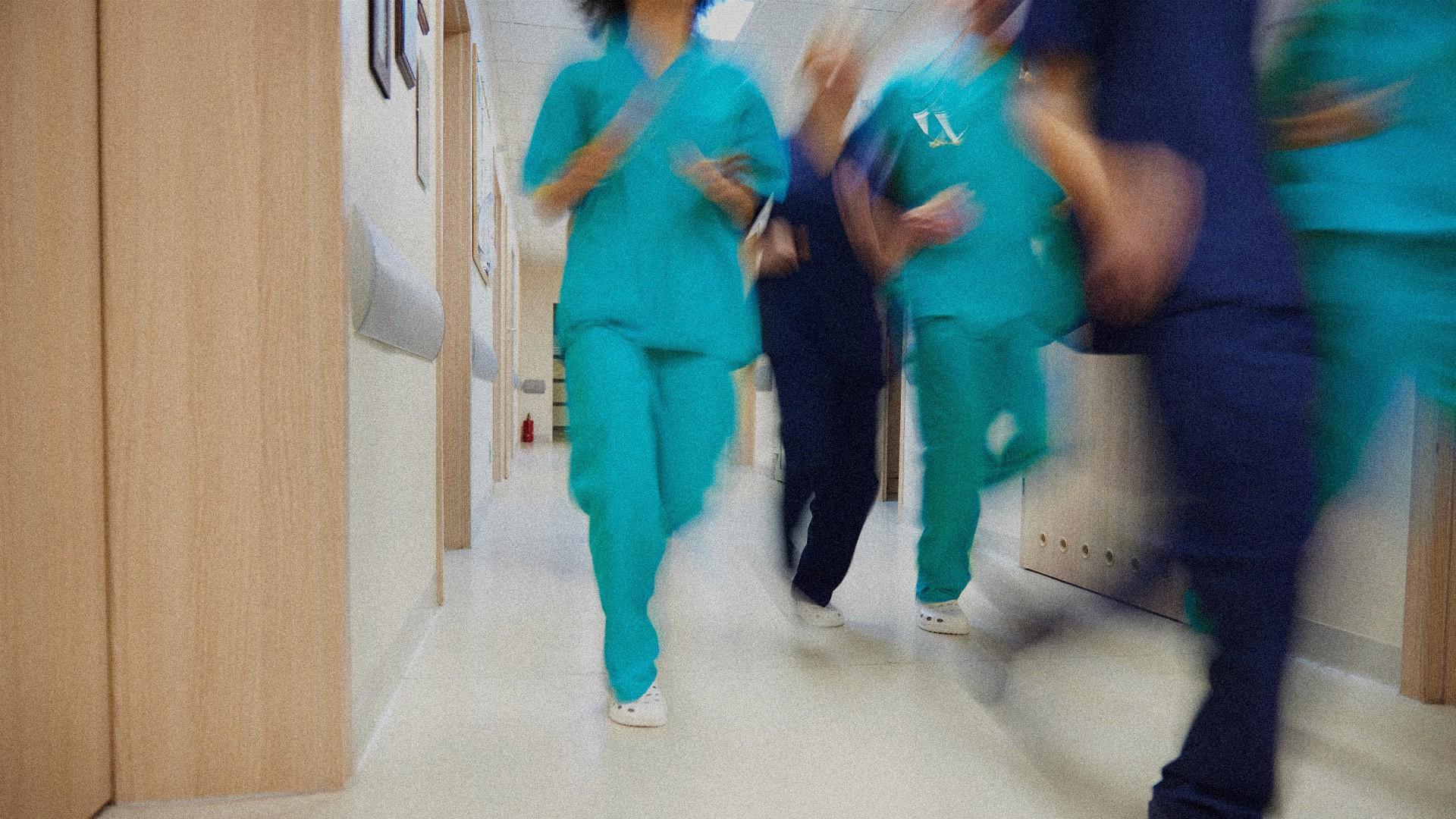 A group of nurses and doctors walking through a hallway of a hospital with motion blur placed on the image.