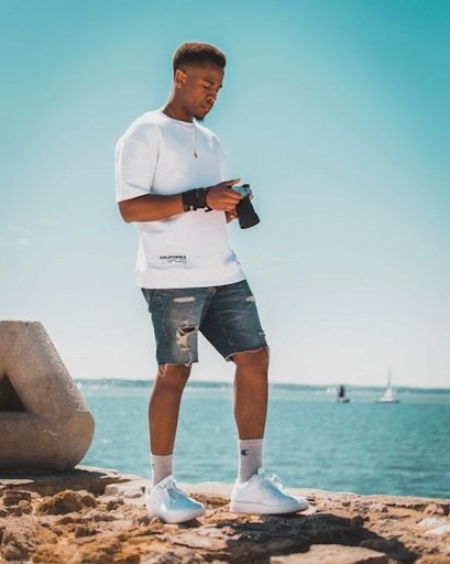 A boy stands on the beach with a camera in hand.