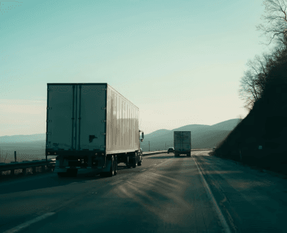 Box truck driving on a highway through the mountains, representing interstate trucking subject to FMCSA insurance requirements.
