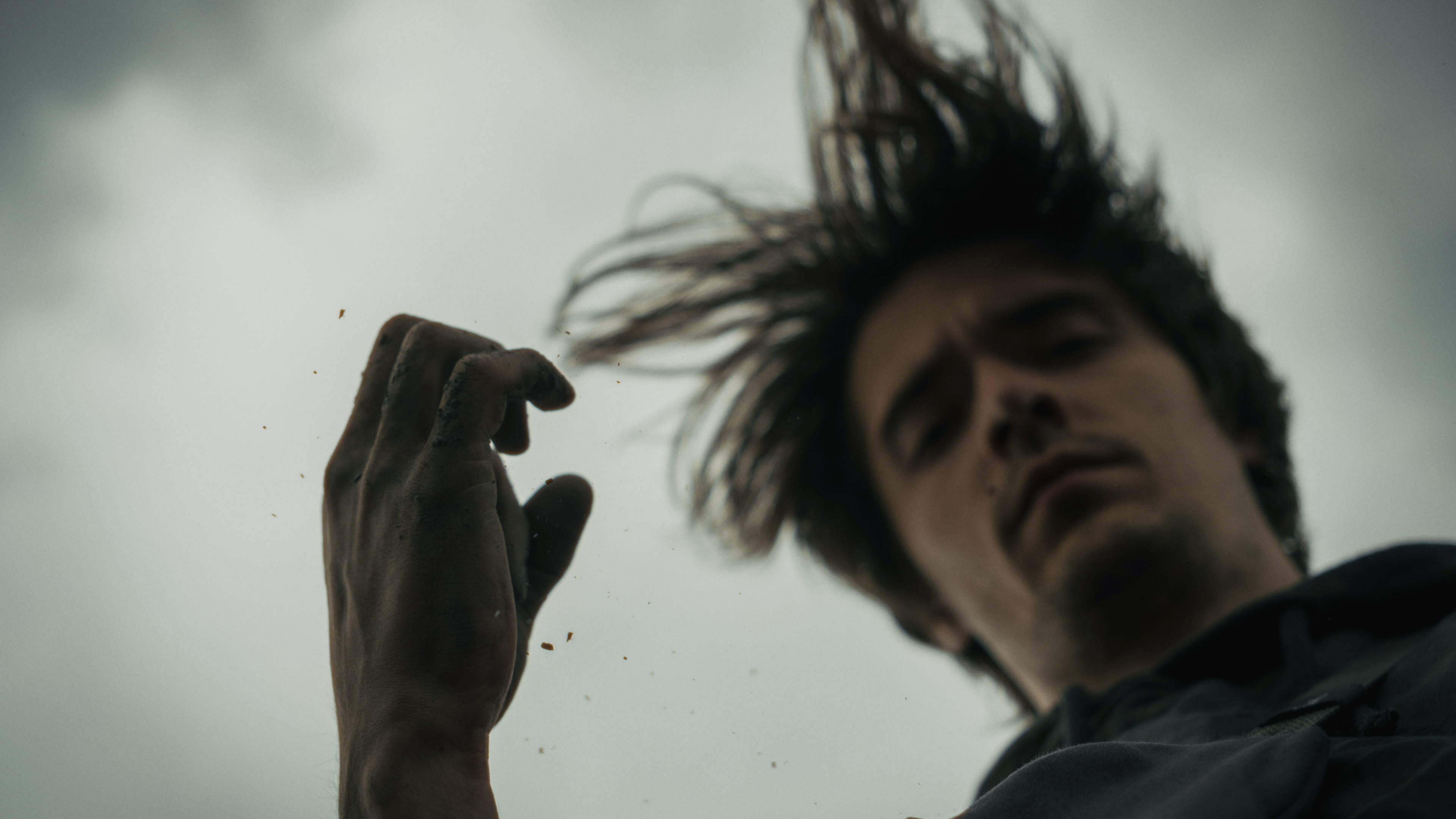 Artistic portrait shot from below, capturing a man's expression against the sky.