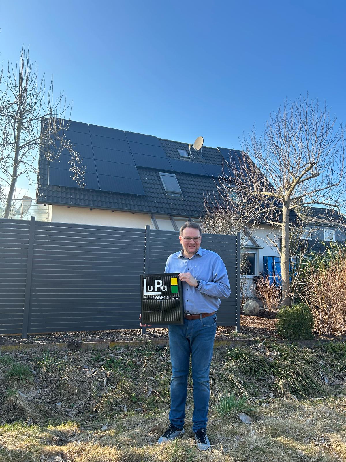 Marc aus Holzminden vor seinem Haus mit PV-Anlage lächelt in die Kamera