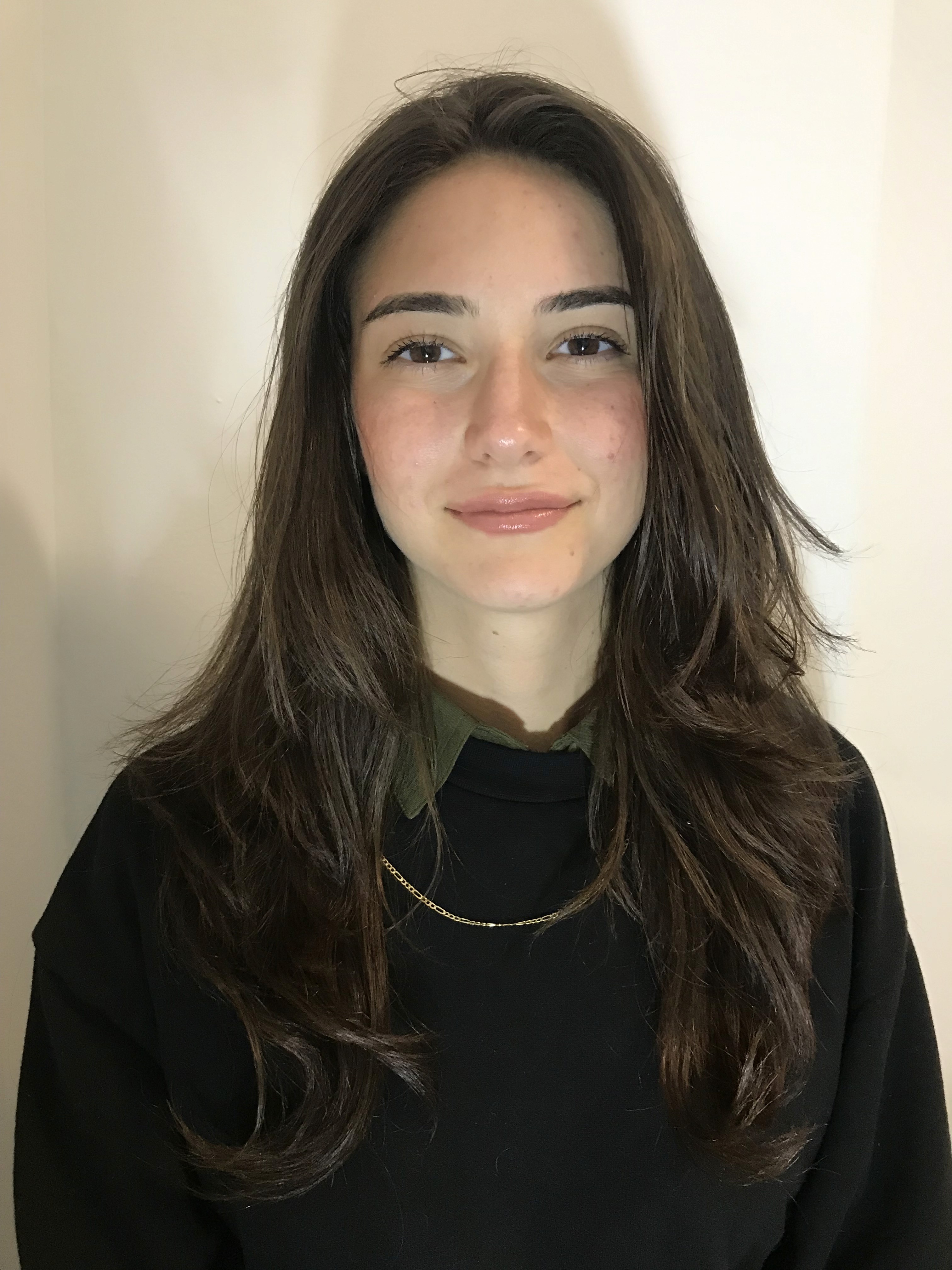 A thoughtful young person with dark hair gazes to the side, captured in soft black and white lighting.