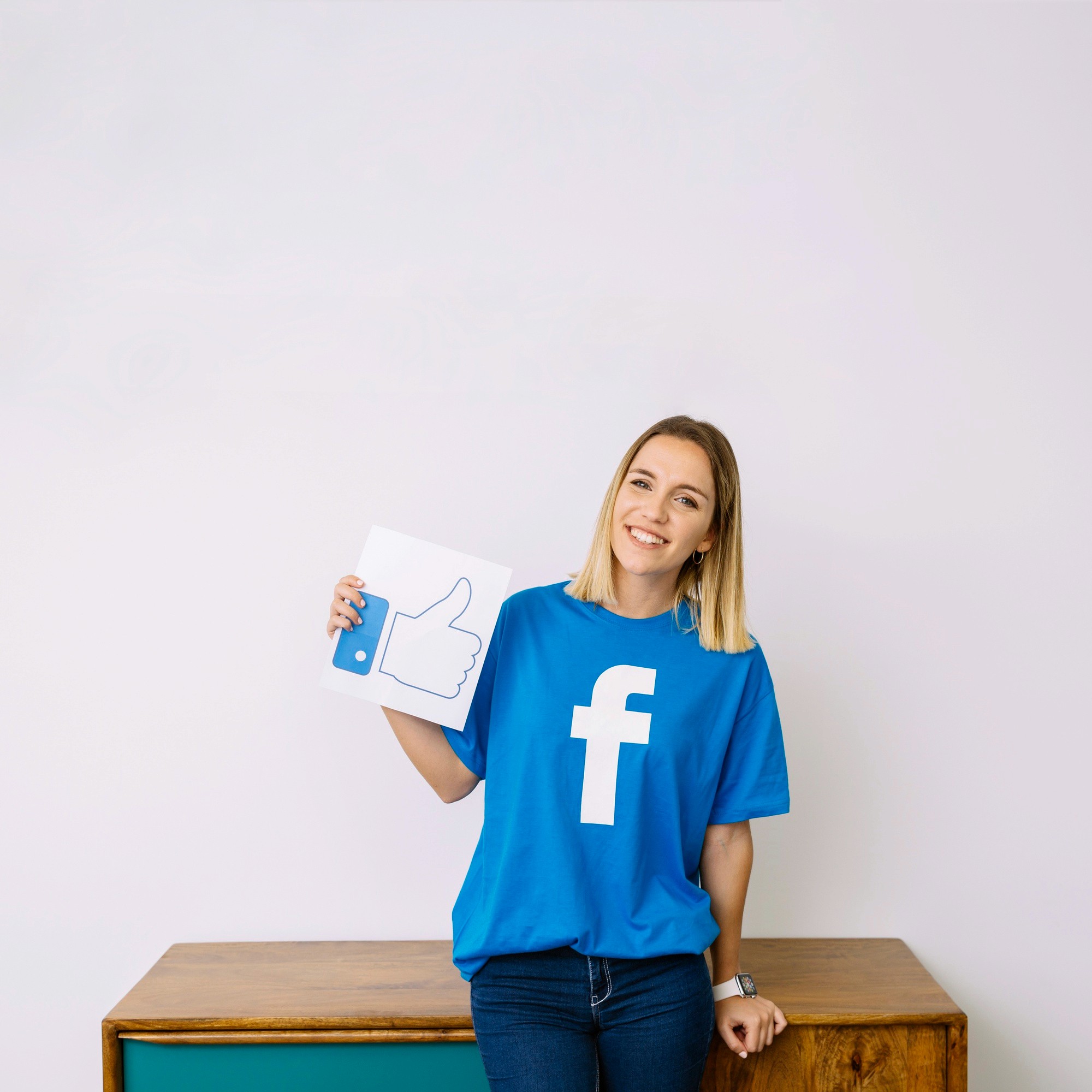 A woman proudly displays a Facebook sign, showcasing her support for the social media platform.