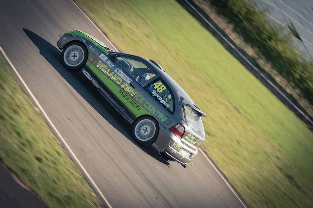 Race car speeds down a track with green grass.