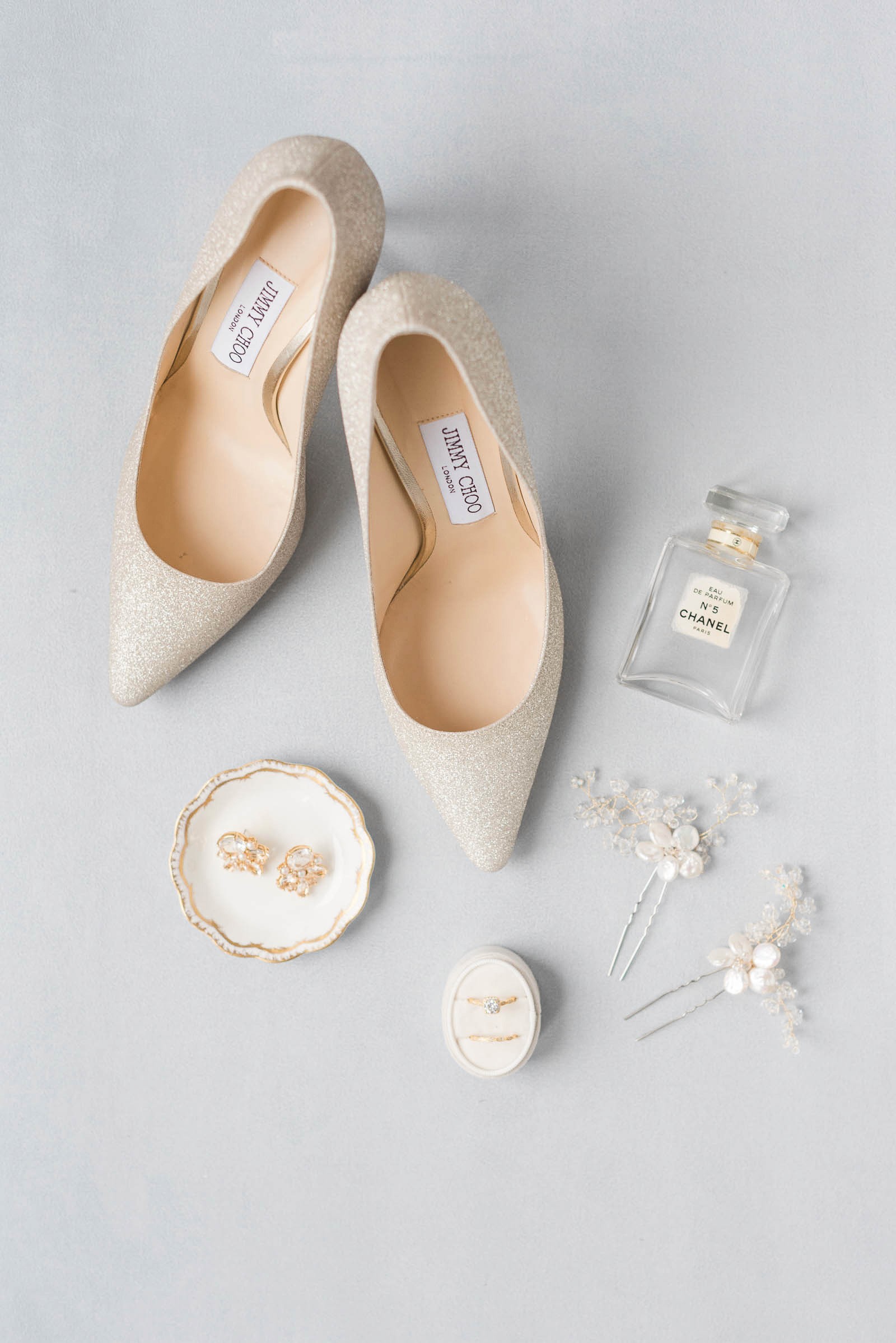 Wedding flat lay of Jimmy Choo shoes, perfume, and bride's wedding accessories.