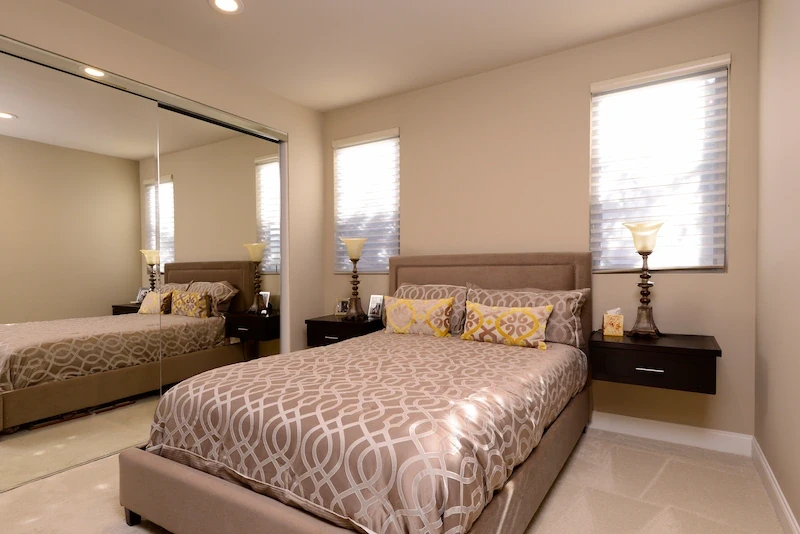 Cozy guest bedroom with patterned bedding and mirrored accents in Harbor Ridge Transitional Remodel.