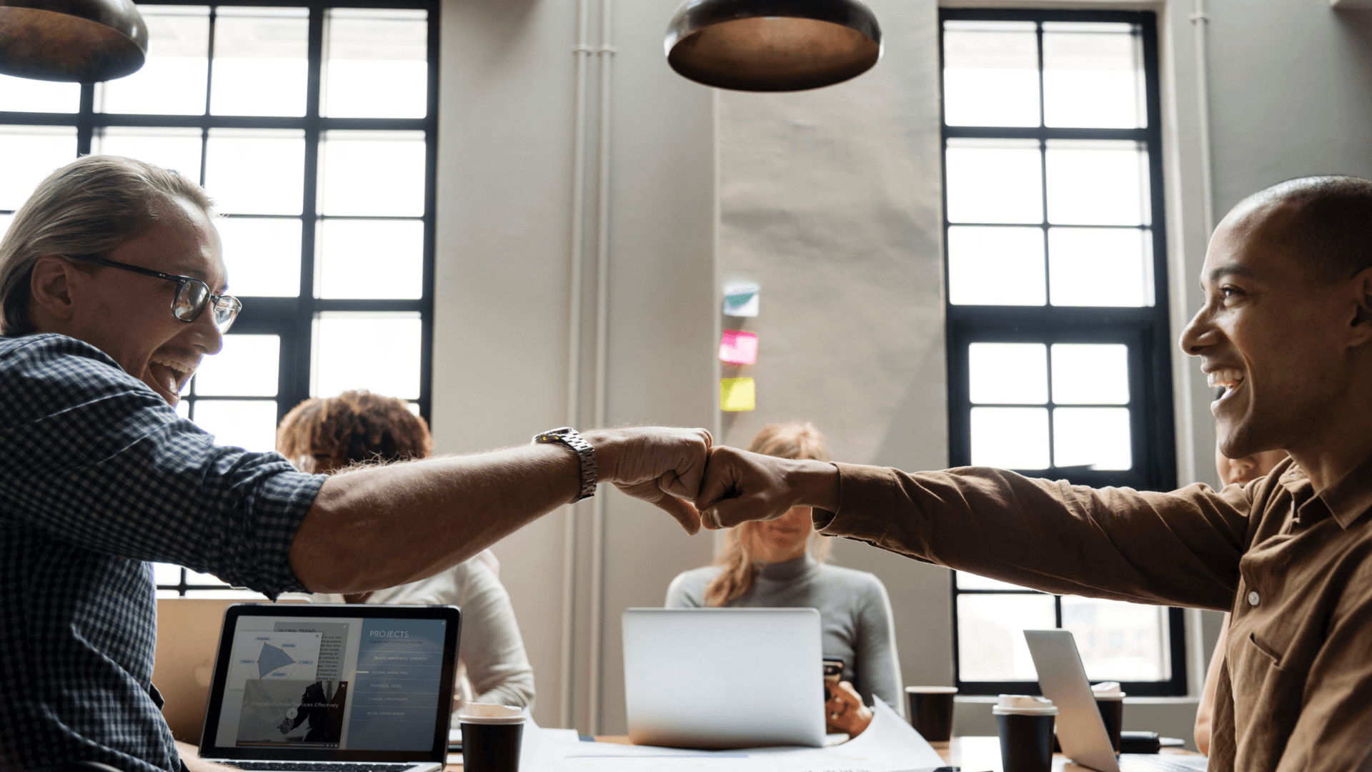 Two people shaking hands over a table in an office environment