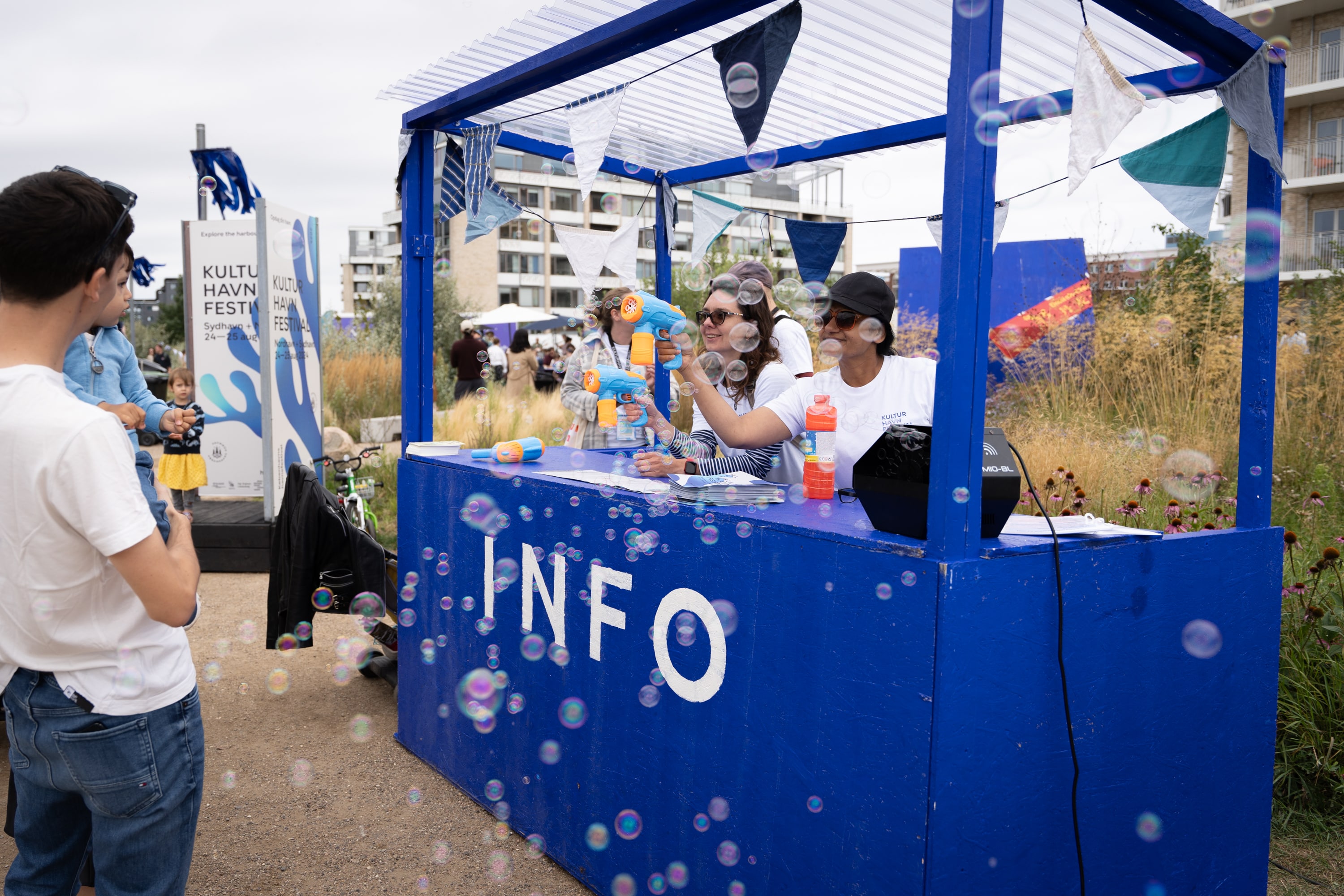 Frivillige i København blæser sæbebolber i infobod til glæde for børn og deres forældre.