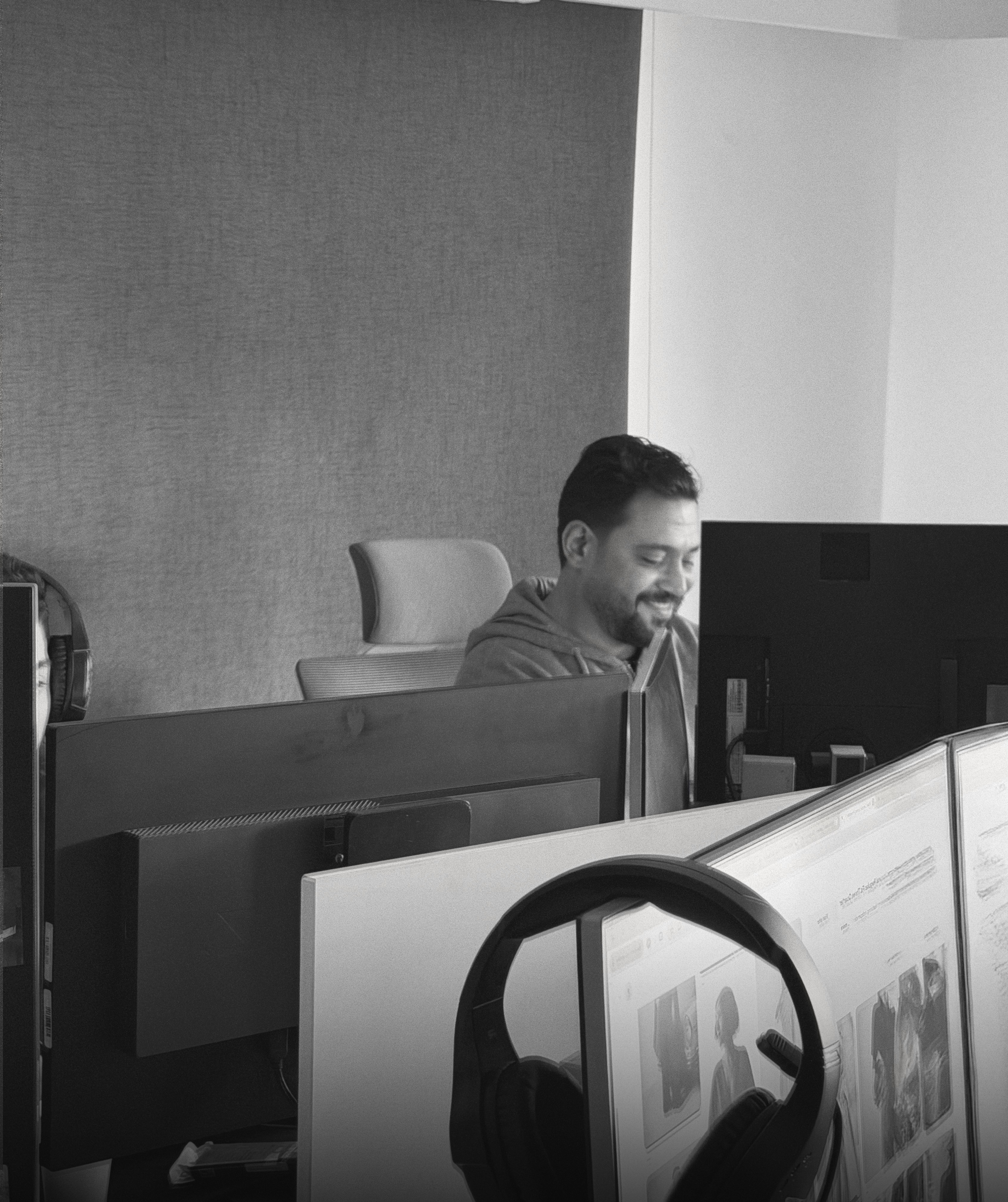 Black and white photo of two people looking at a computer screen with papers on wall