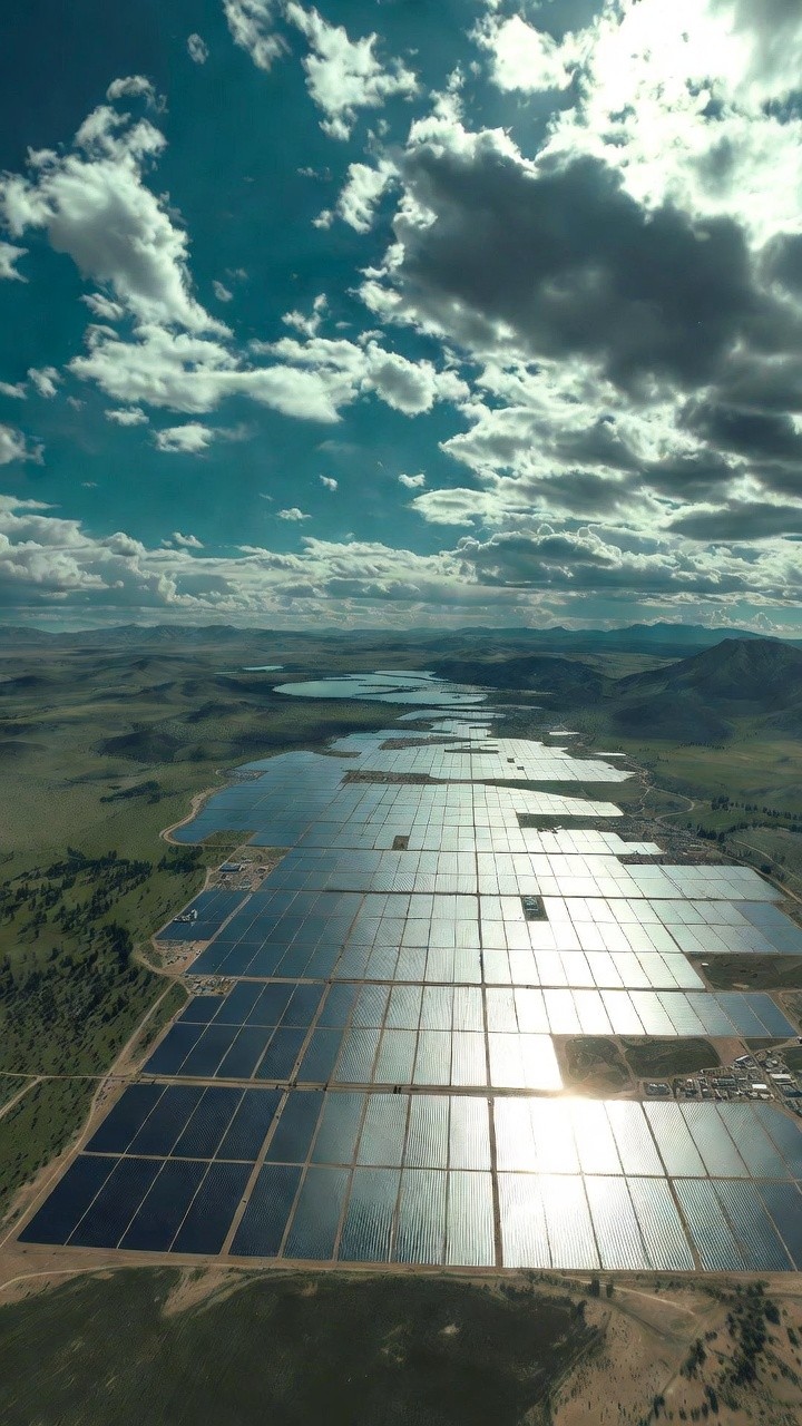 Wind turbine overlooking bright green farmland and scattered buildings