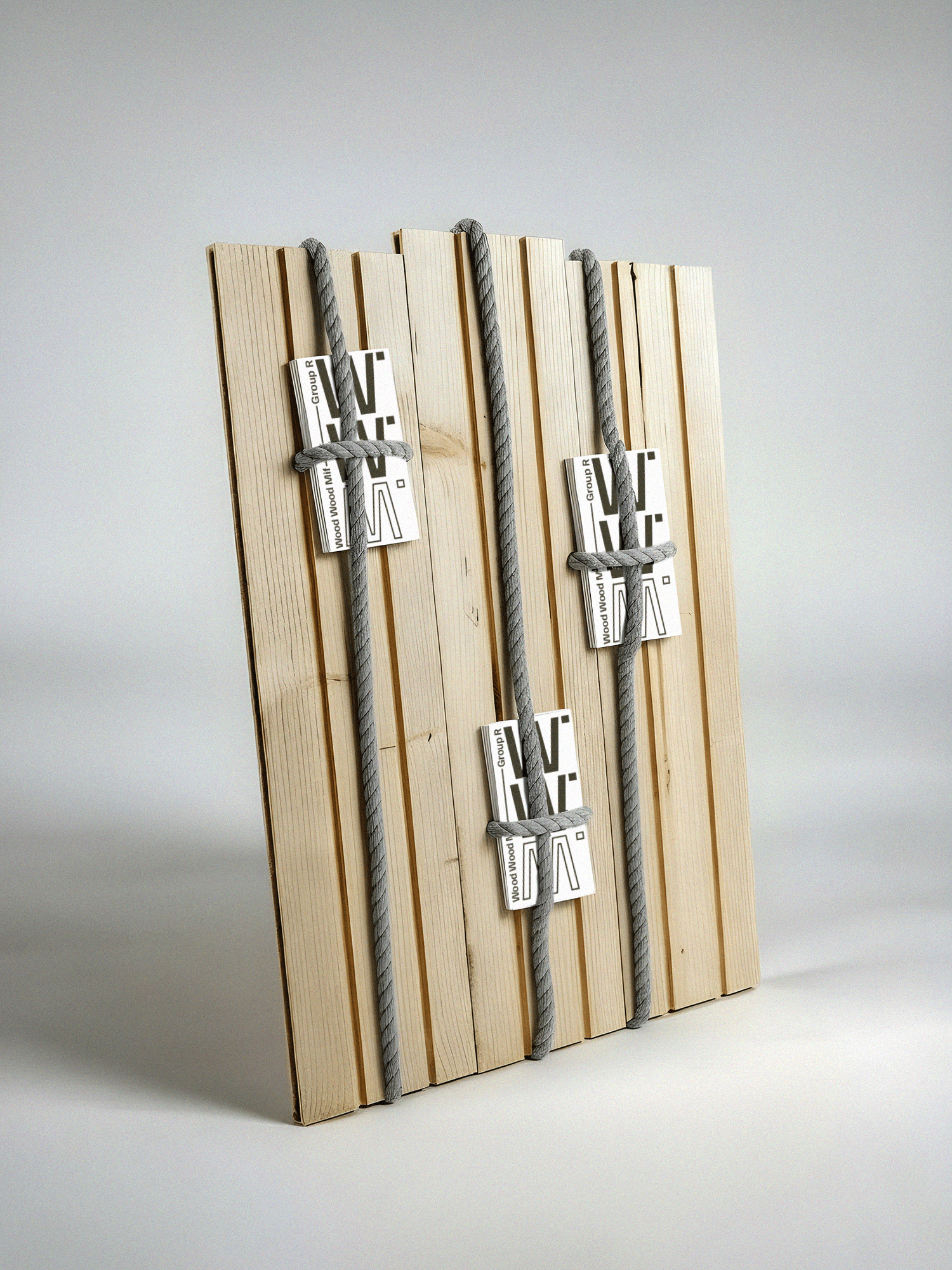 Un mockup de livre épuré et minimaliste, présenté debout contre un mur gris clair. La couverture met en avant une typographie forte “W W M.”, empilée verticalement, tandis que la tranche affiche la mention « Wood Wood Mif – Group R ». Le contraste noir sur blanc, volontairement sobre et précis, donne à l’ensemble une esthétique éditoriale contemporaine, évoquant clairement l’univers des catalogues de musée.