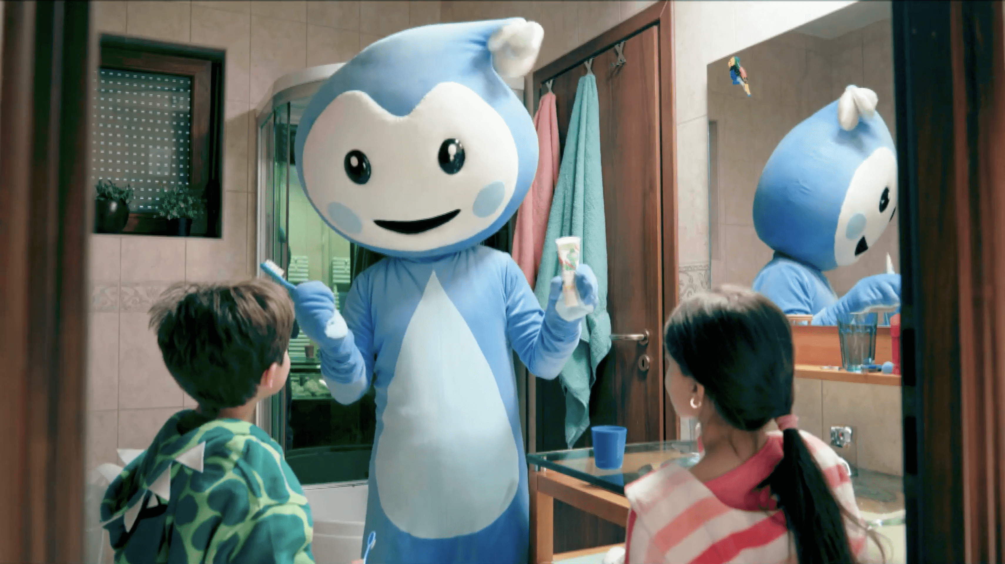 Cseppbarát kék kabalafigurája a fürdőben, kezében fogkefével és fogkrémmel tanítja helyes fogmosásra a gyerekeket.