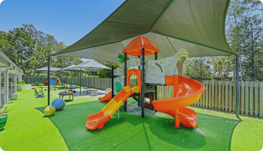 Outdoor playground at Kaleidoscope Kids Goodna childcare centre featuring slides, shaded areas and fun equipment for active learning.