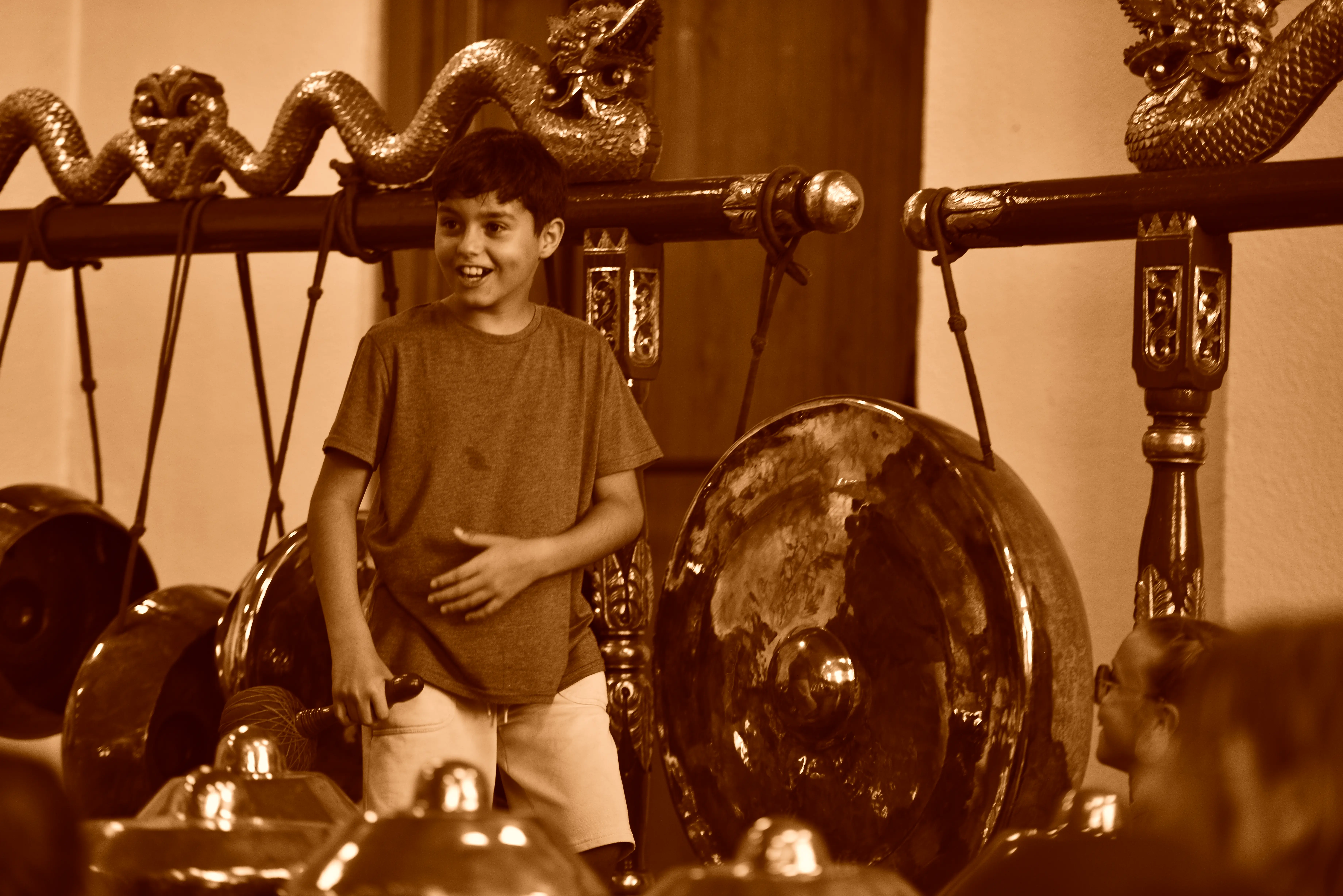 Un garçon souriant devant un gong javanais.