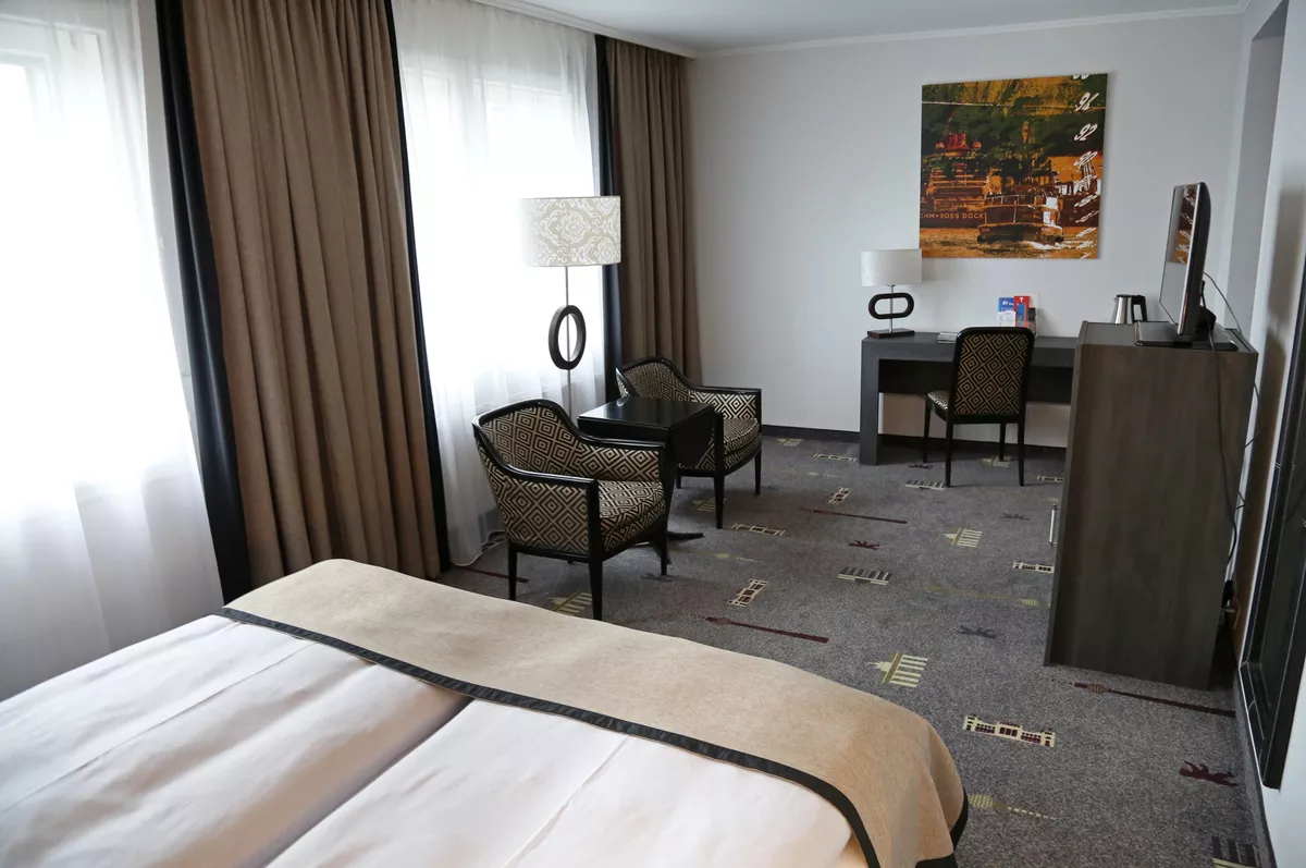 Bild vom Studio Zimmer vom Bett aus fotografiert mit Blick auf Coach, Sessel, Schreibtisch und TV