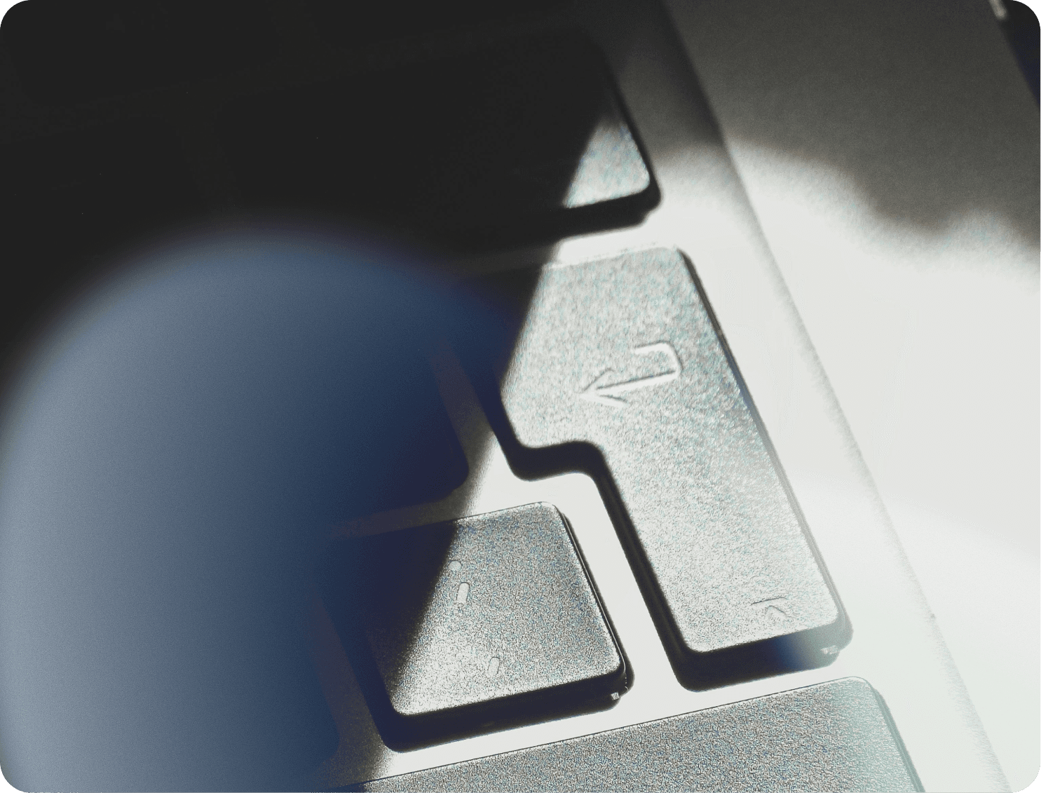 A winding road cuts through rocky terrain, surrounded by patches of green grass and illuminated by sunlight.